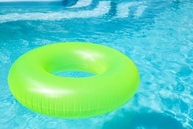 Bright inflatable ring floating in swimming pool on sunny day