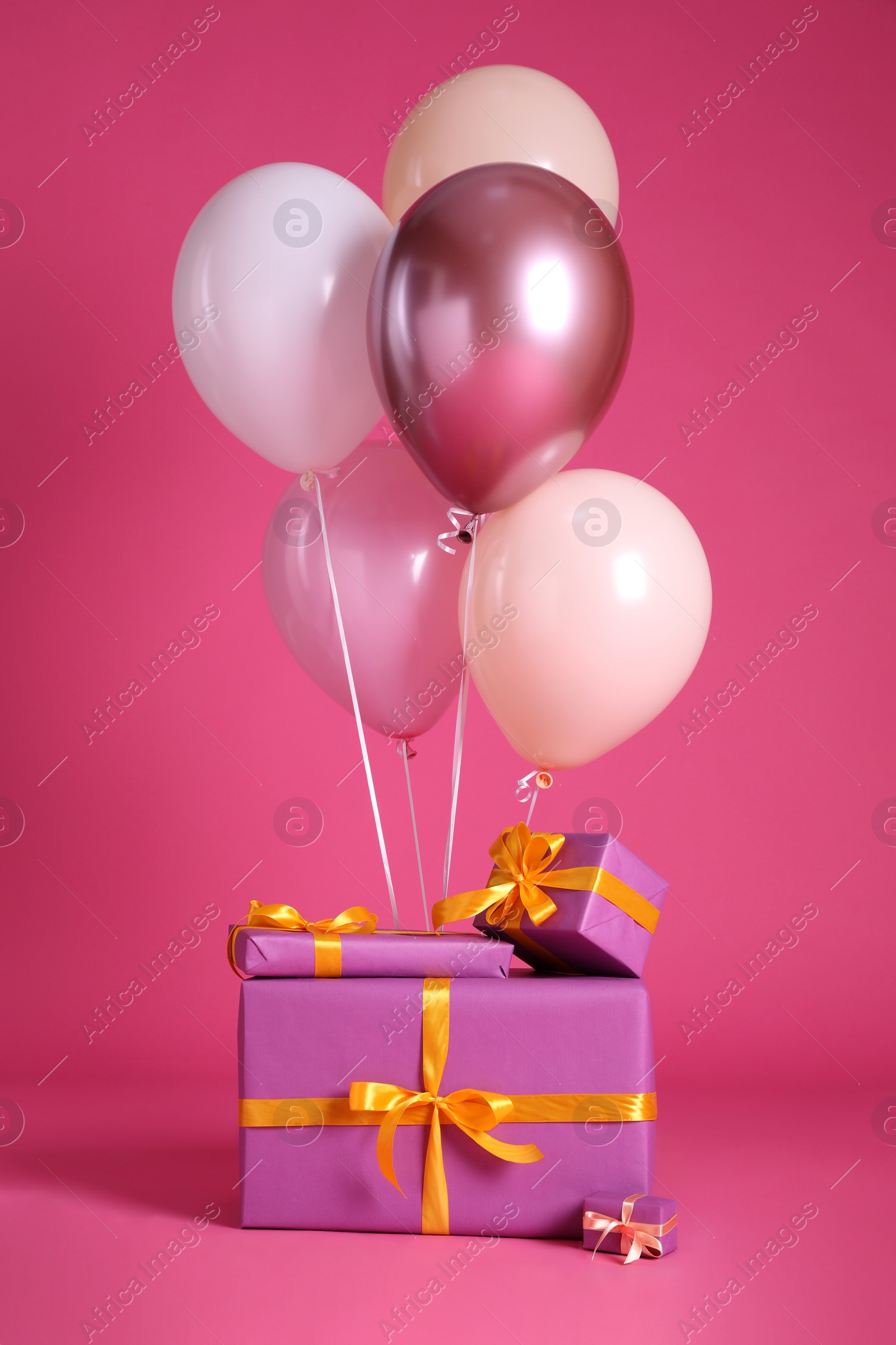 Photo of Gift boxes and balloons near bright pink ​background