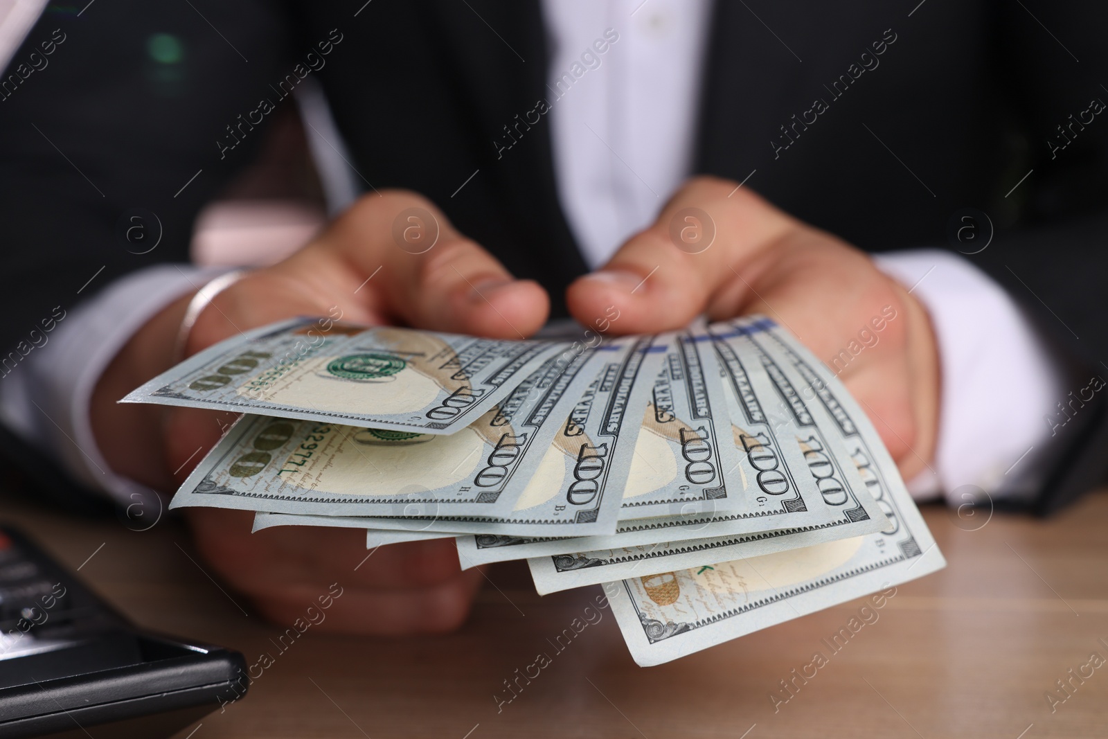 Photo of Money exchange. Man counting dollar banknotes at wooden table, closeup