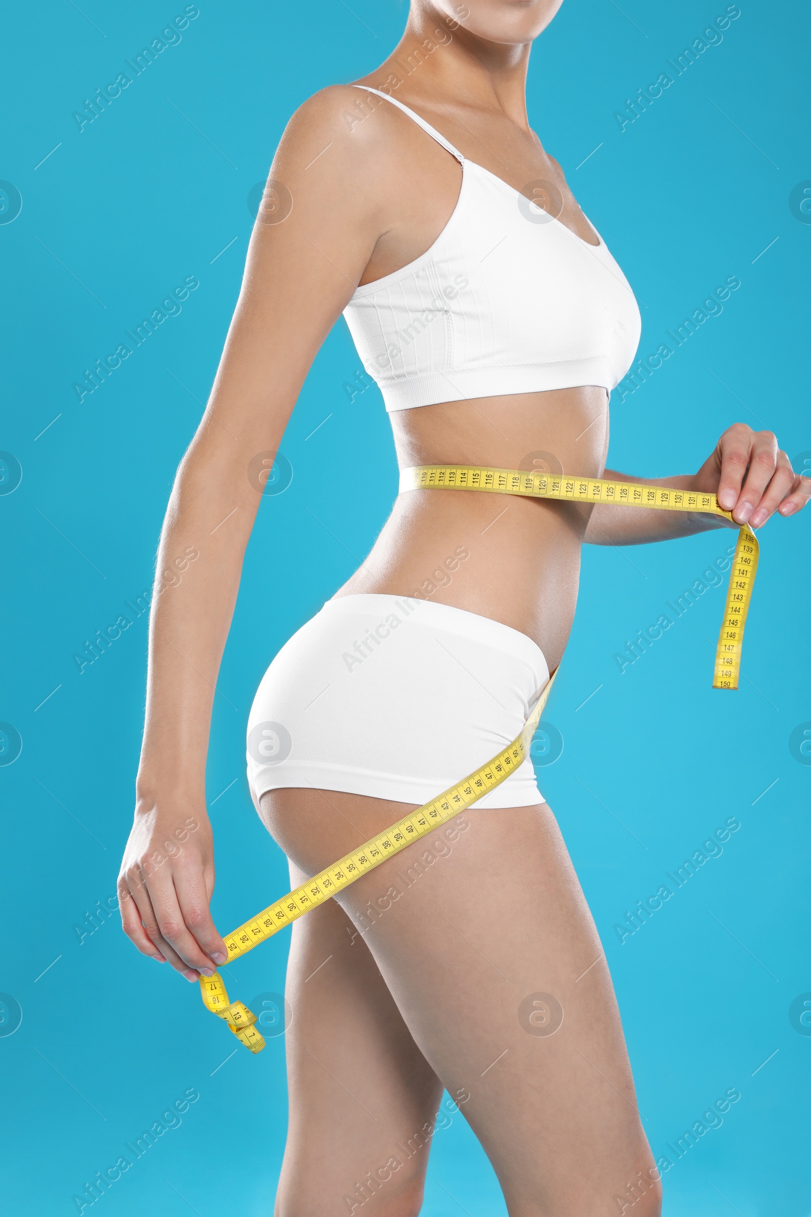 Photo of Slim young woman with smooth gentle skin in underwear measuring body on color background