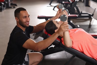 Young woman working out with professional trainer in modern gym