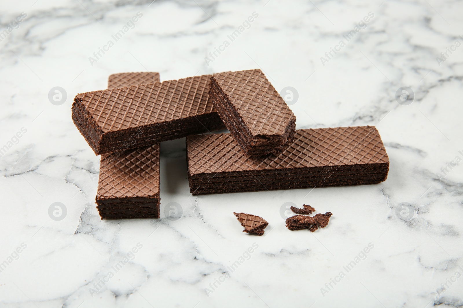 Photo of Delicious crispy chocolate wafers on marble background