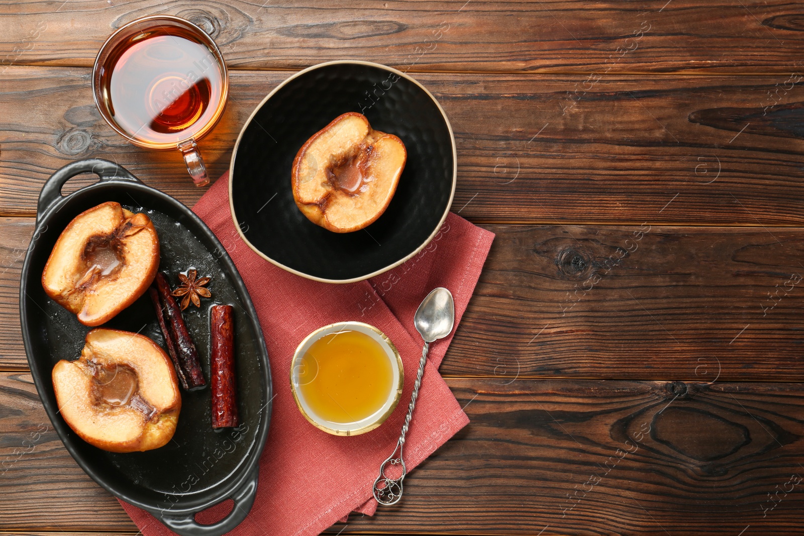 Photo of Tasty baked quinces served with honey and tea on wooden table, flat lay. Space for text