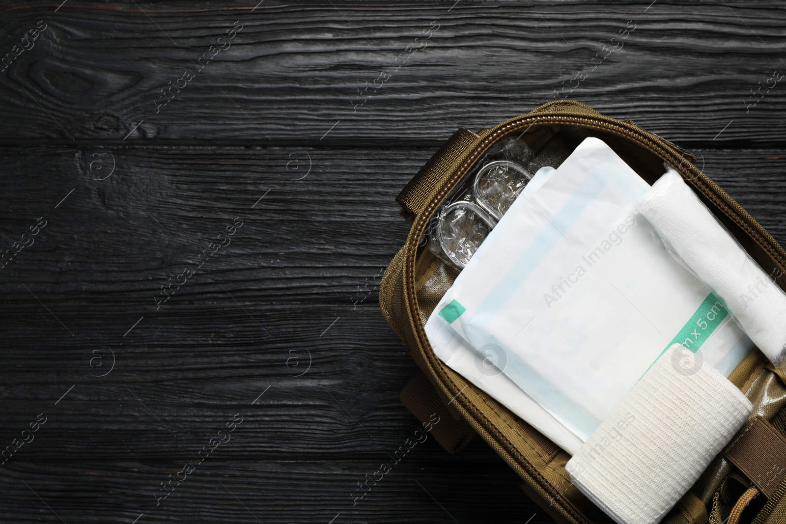 Photo of Military first aid kit on wooden table, top view. Space for text