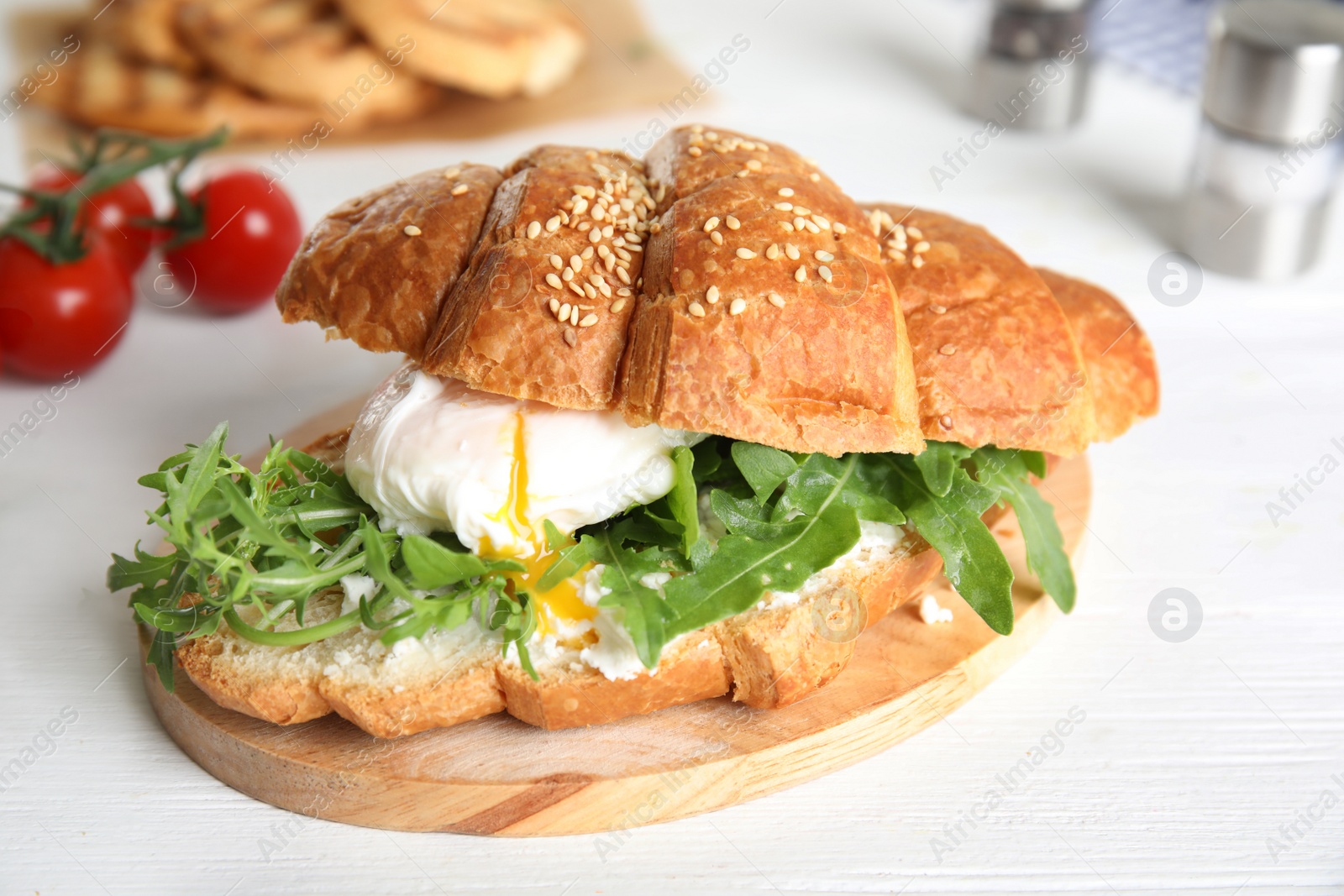 Photo of Delicious croissant with arugula and egg on white wooden table, closeup