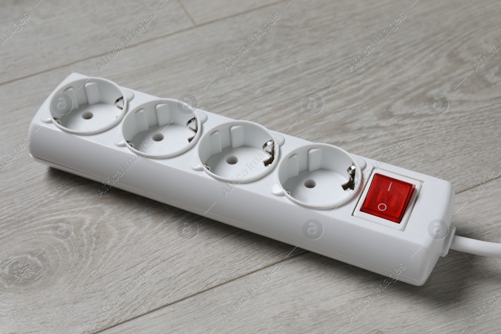 Photo of Power strip on wooden floor, closeup. Electrician's equipment