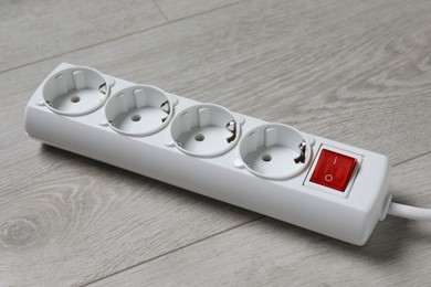 Photo of Power strip on wooden floor, closeup. Electrician's equipment