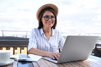 Photo of Beautiful woman with glasses using laptop at outdoor cafe
