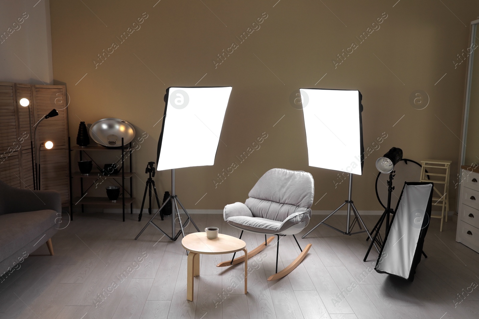 Photo of Interior of modern photo studio with rocking chair, table and professional equipment