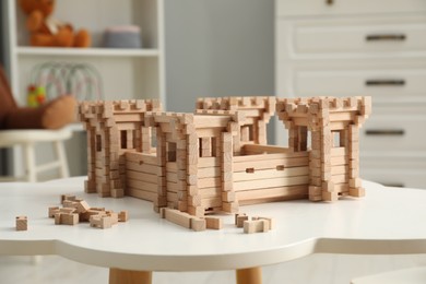 Photo of Wooden fortress and building blocks on white table indoors. Children's toy