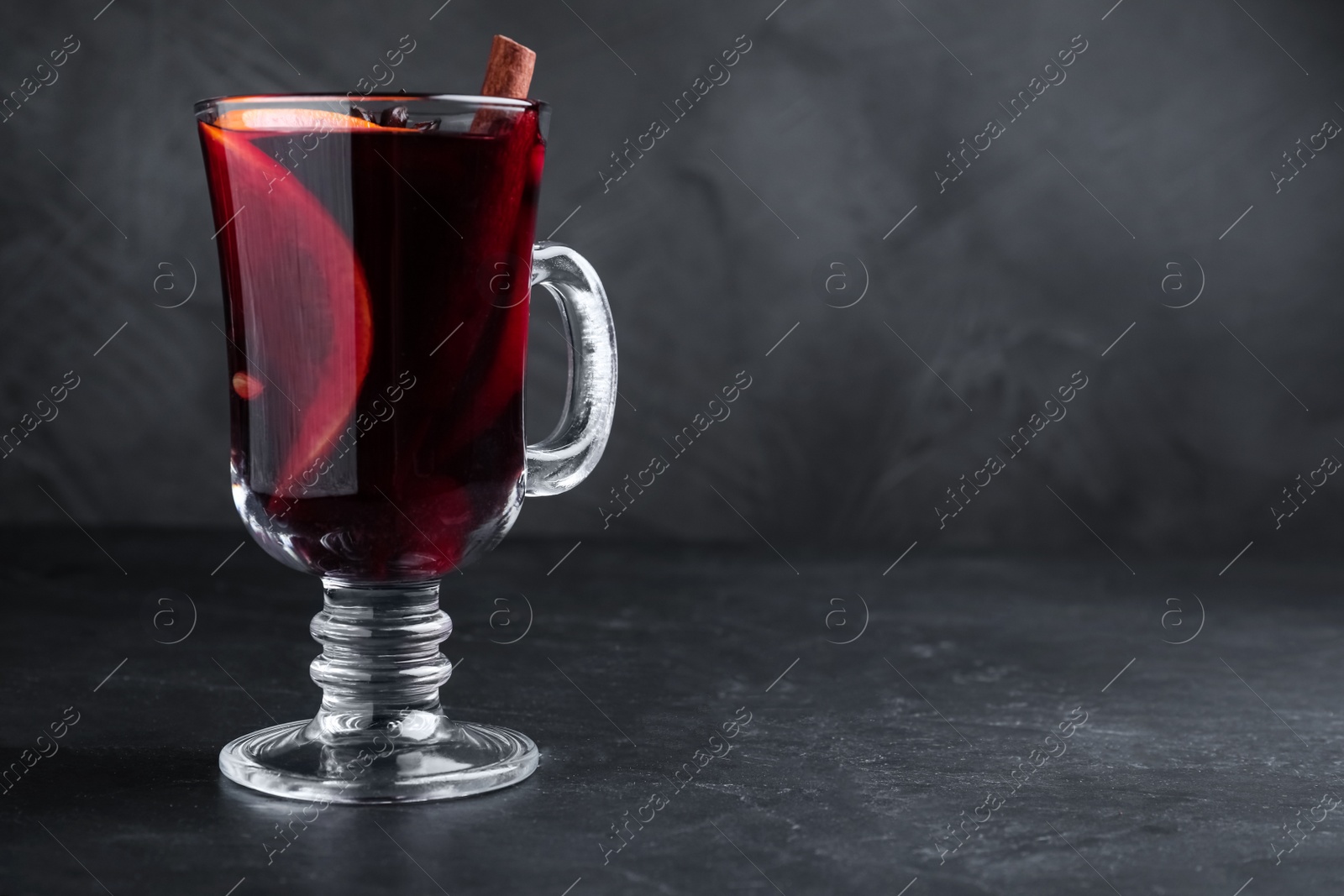 Photo of Aromatic mulled wine on black table, space for text