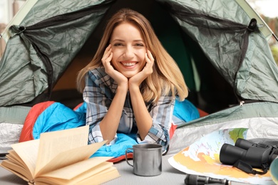 Photo of Young woman in sleeping bag looking outside of tent