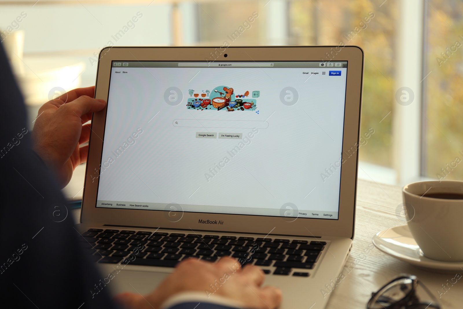 Photo of MYKOLAIV, UKRAINE - OCTOBER 27, 2020: Man using Google search engine on MacBook Air laptop at table indoors, closeup