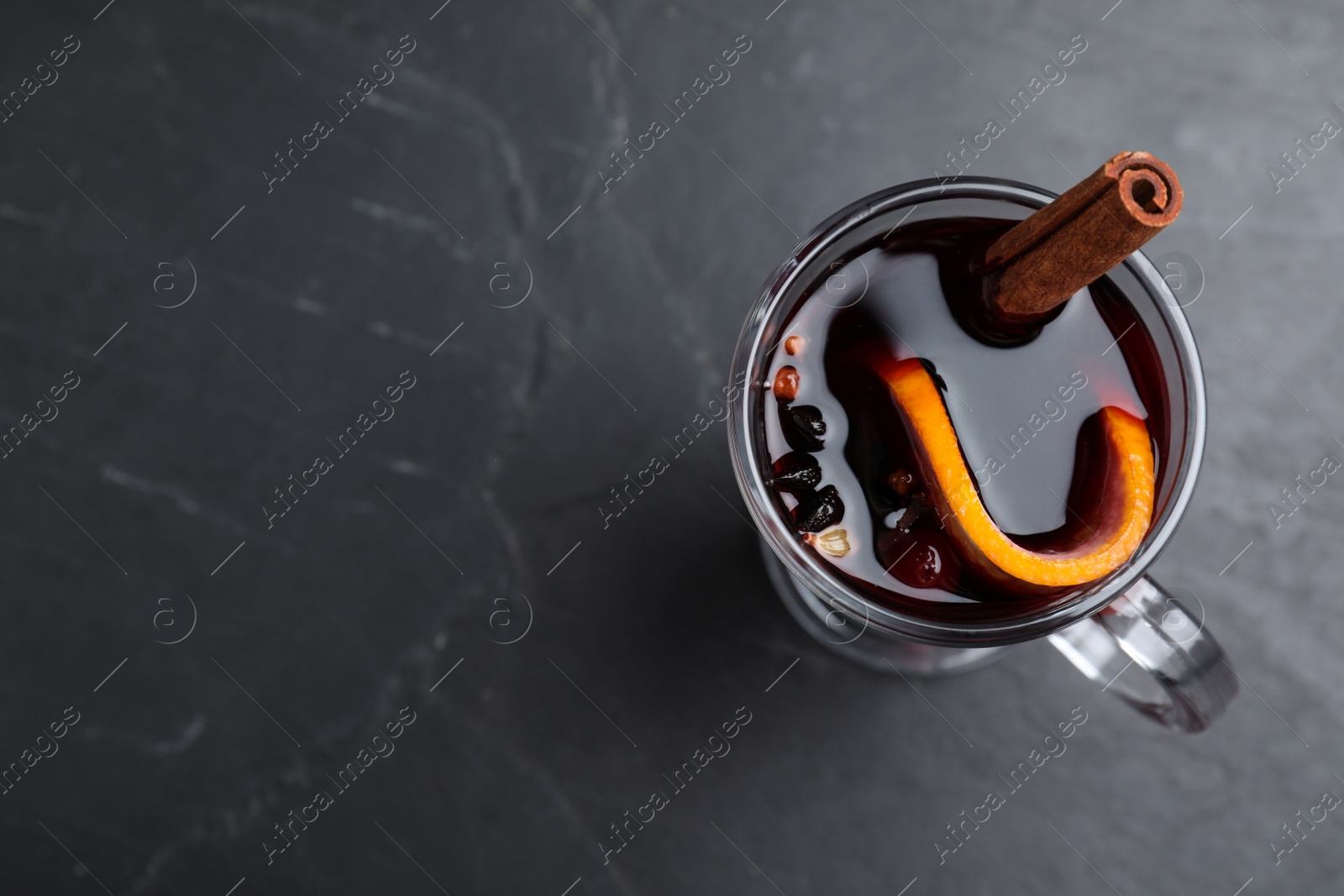 Photo of Aromatic mulled wine on black table, top view. Space for text