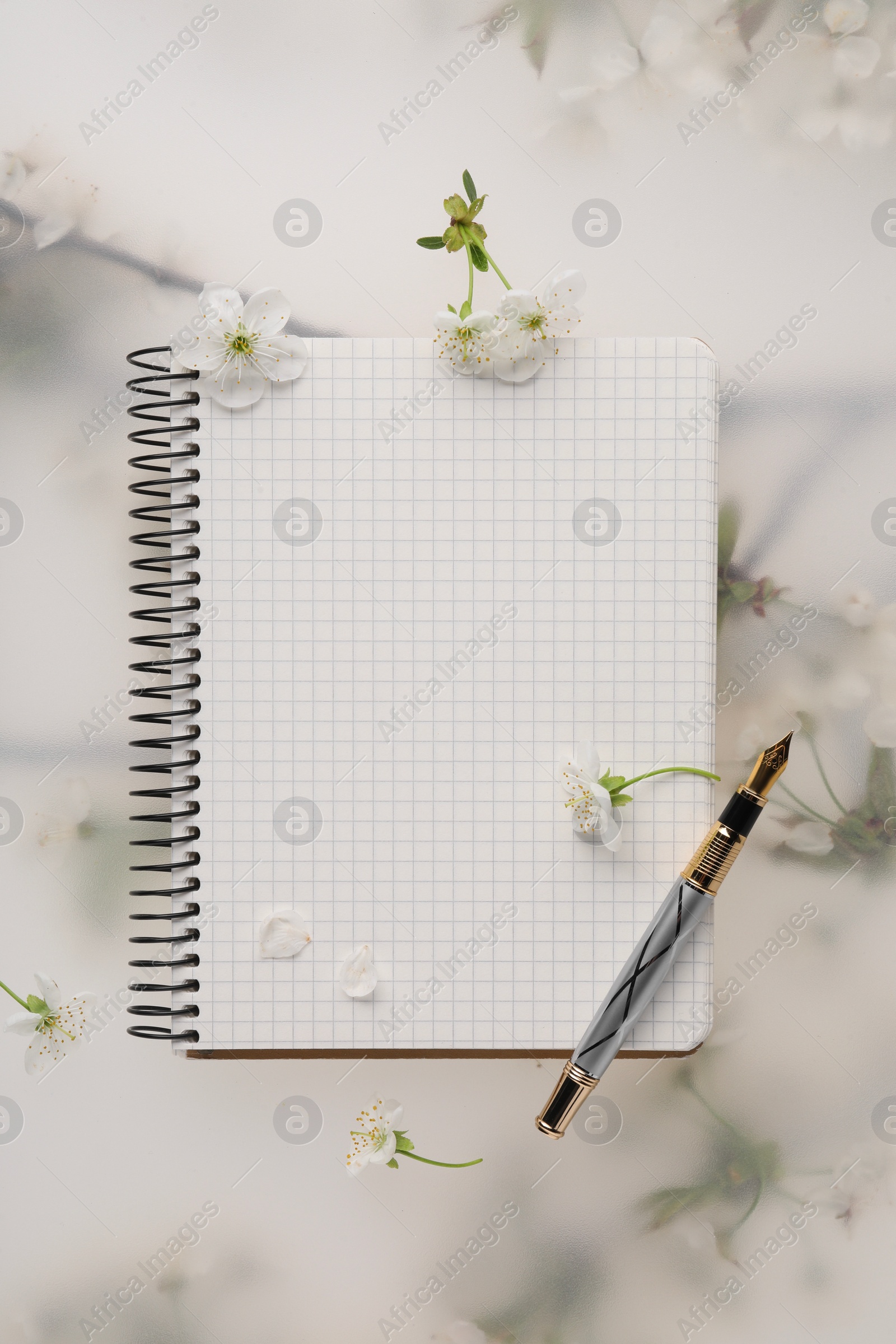 Photo of Guest list. Notebook, pencil and beautiful cherry tree blossoms on spring floral background, flat lay