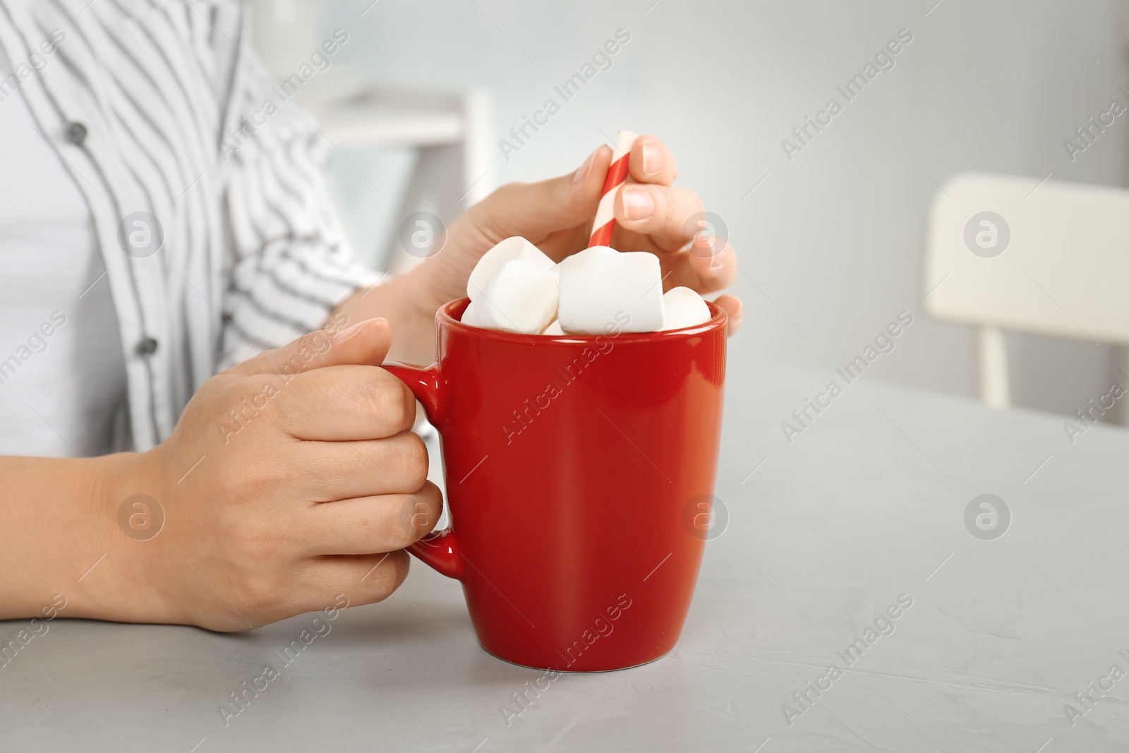 Photo of Young woman with delicious hot cocoa drink at table