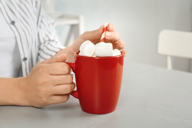 Photo of Young woman with delicious hot cocoa drink at table