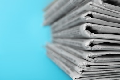 Photo of Stack of newspapers on light blue background, closeup. Journalist's work