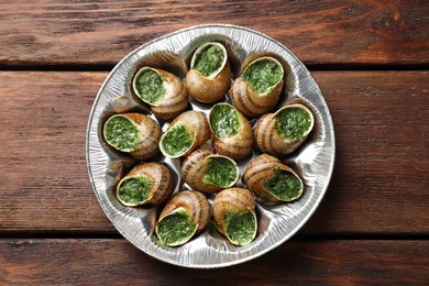 Photo of Delicious cooked snails on wooden table, top view