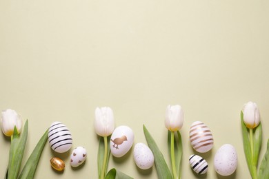 Photo of Flat lay composition of painted Easter eggs and tulip flowers on light green background. Space for text