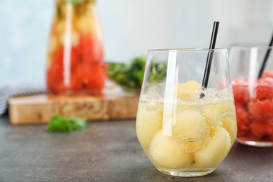 Photo of Glass with tasty melon ball drink on table