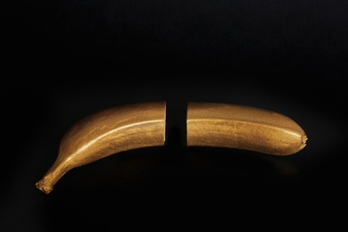 Gold painted cut banana on black background