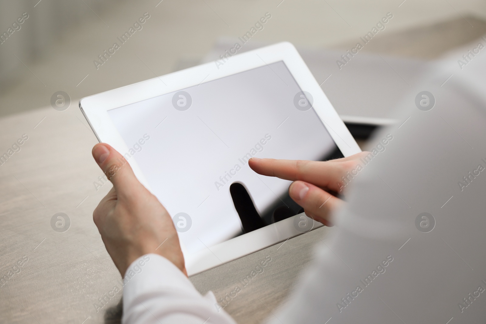 Photo of Man using tablet at wooden table, closeup