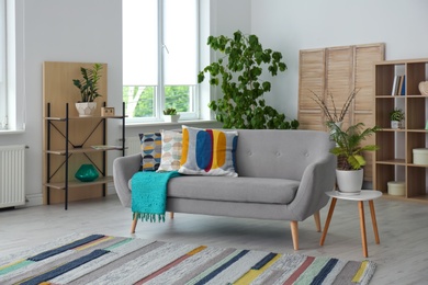 Photo of Elegant living room interior with comfortable sofa and striped carpet