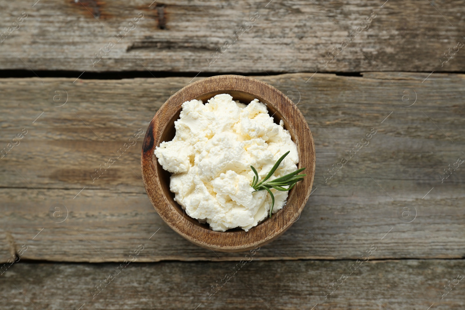 Photo of Delicious tofu cream cheese with rosemary in bowl on wooden table, top view