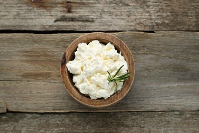 Delicious tofu cream cheese with rosemary in bowl on wooden table, top view