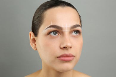 Photo of Eyebrow correction. Young woman with markings on face against grey background