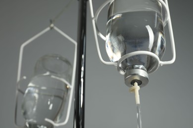 Photo of IV infusion set on pole against grey background, closeup