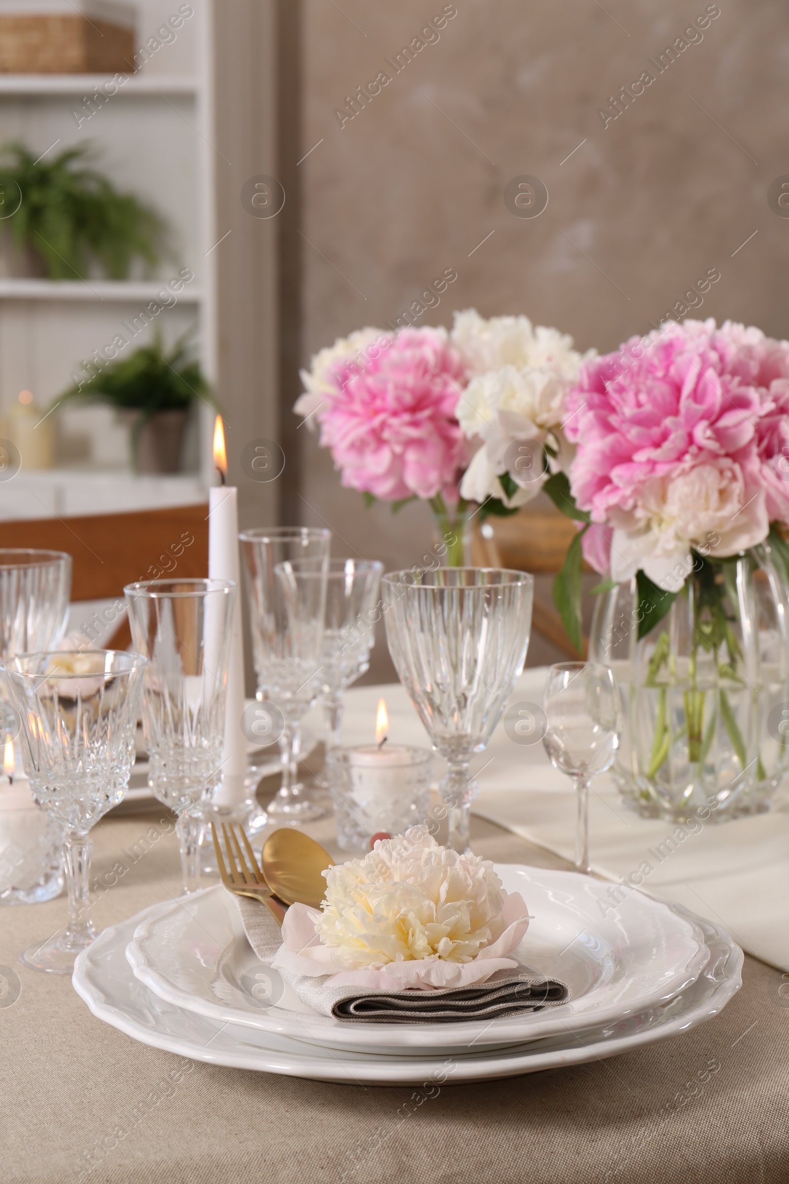 Photo of Stylish table setting with beautiful peonies and burning candles indoors