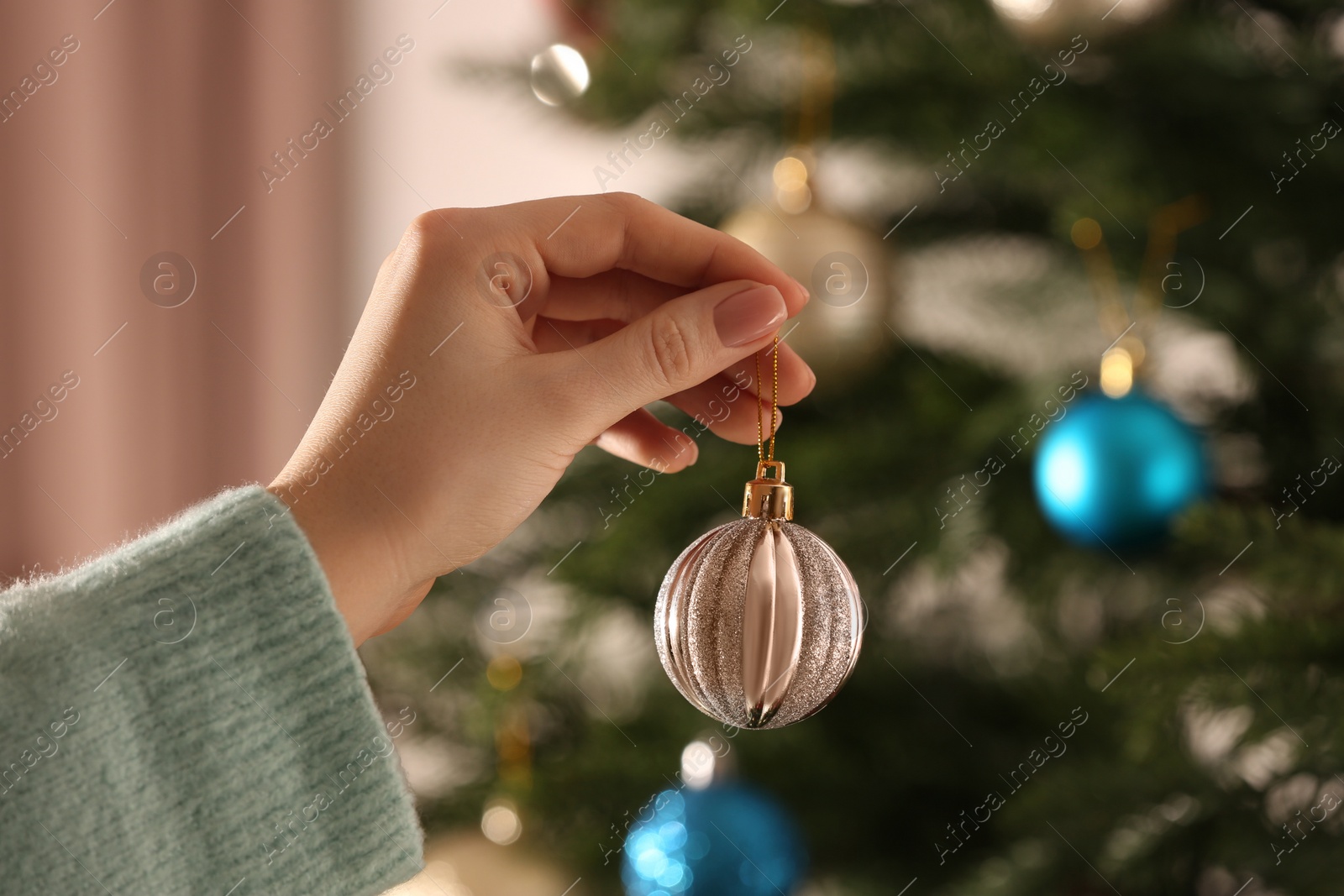 Photo of Woman with shiny Christmas ball near tree indoors, closeup. Space for text