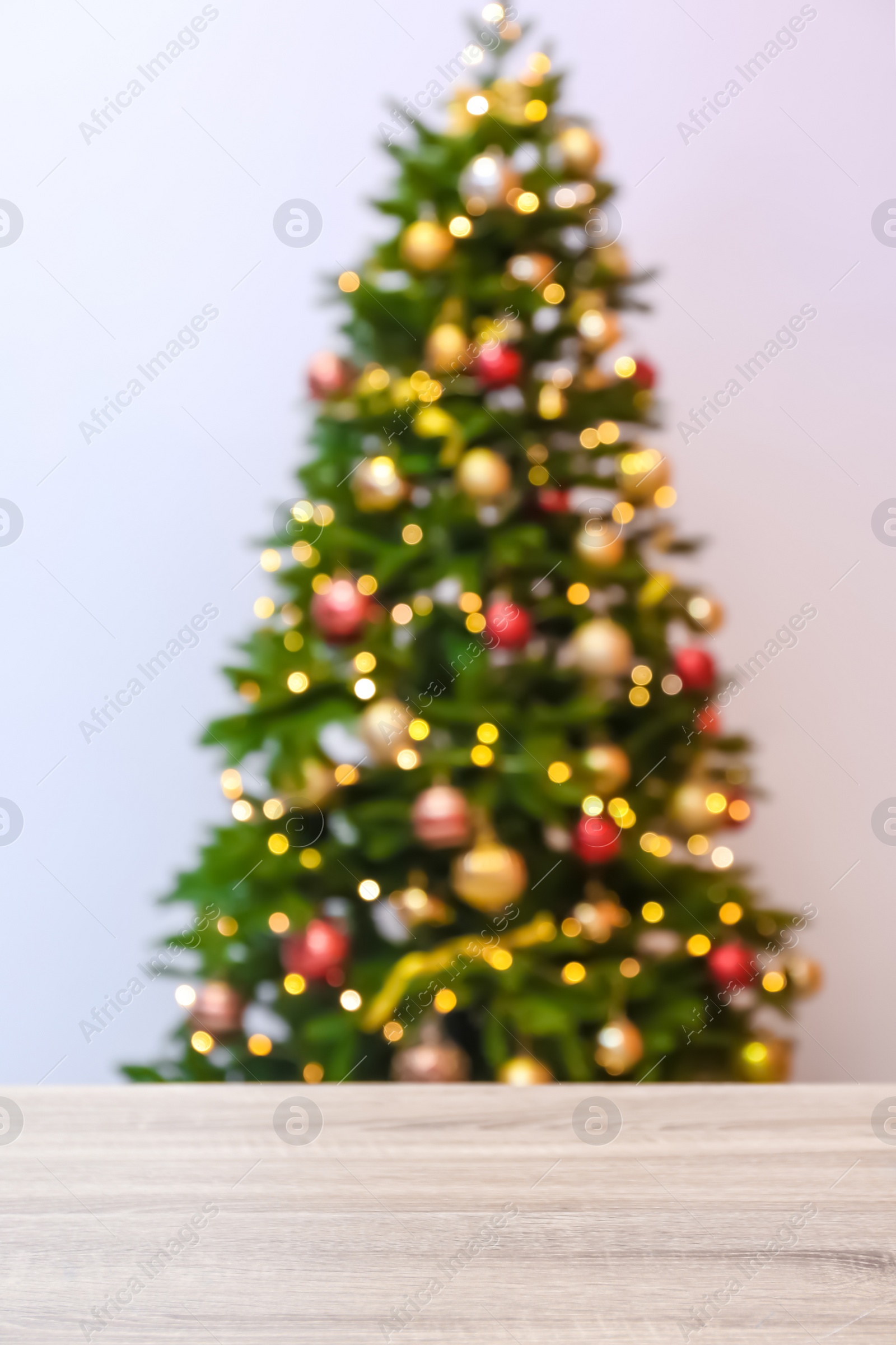 Photo of Wooden table and blurred Christmas tree with fairy lights on background