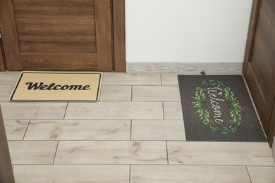 Photo of Beautiful doormats with word Welcome on floor near doors in hall