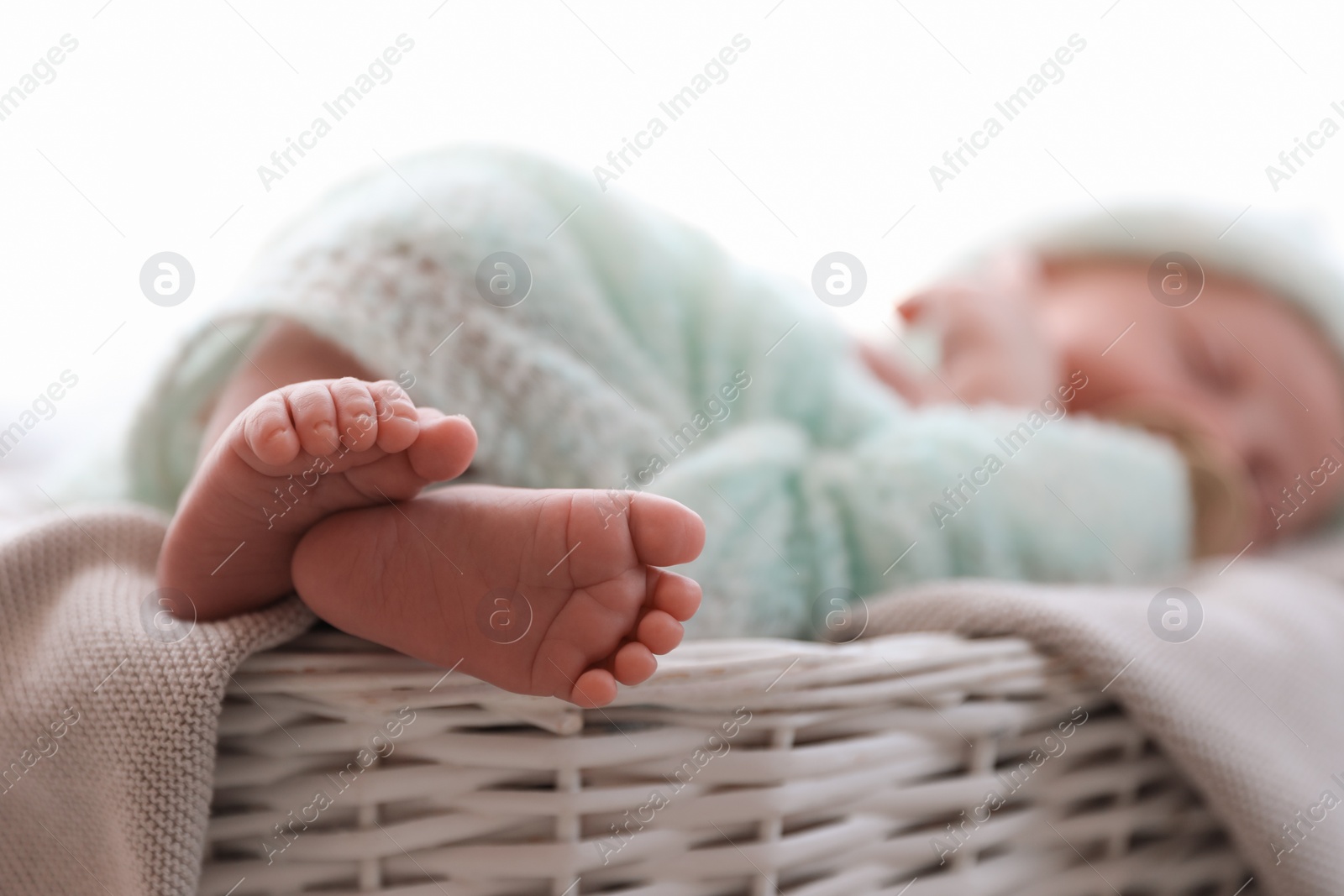 Photo of Newborn baby lying on plaid in basket, closeup of legs. Space for text