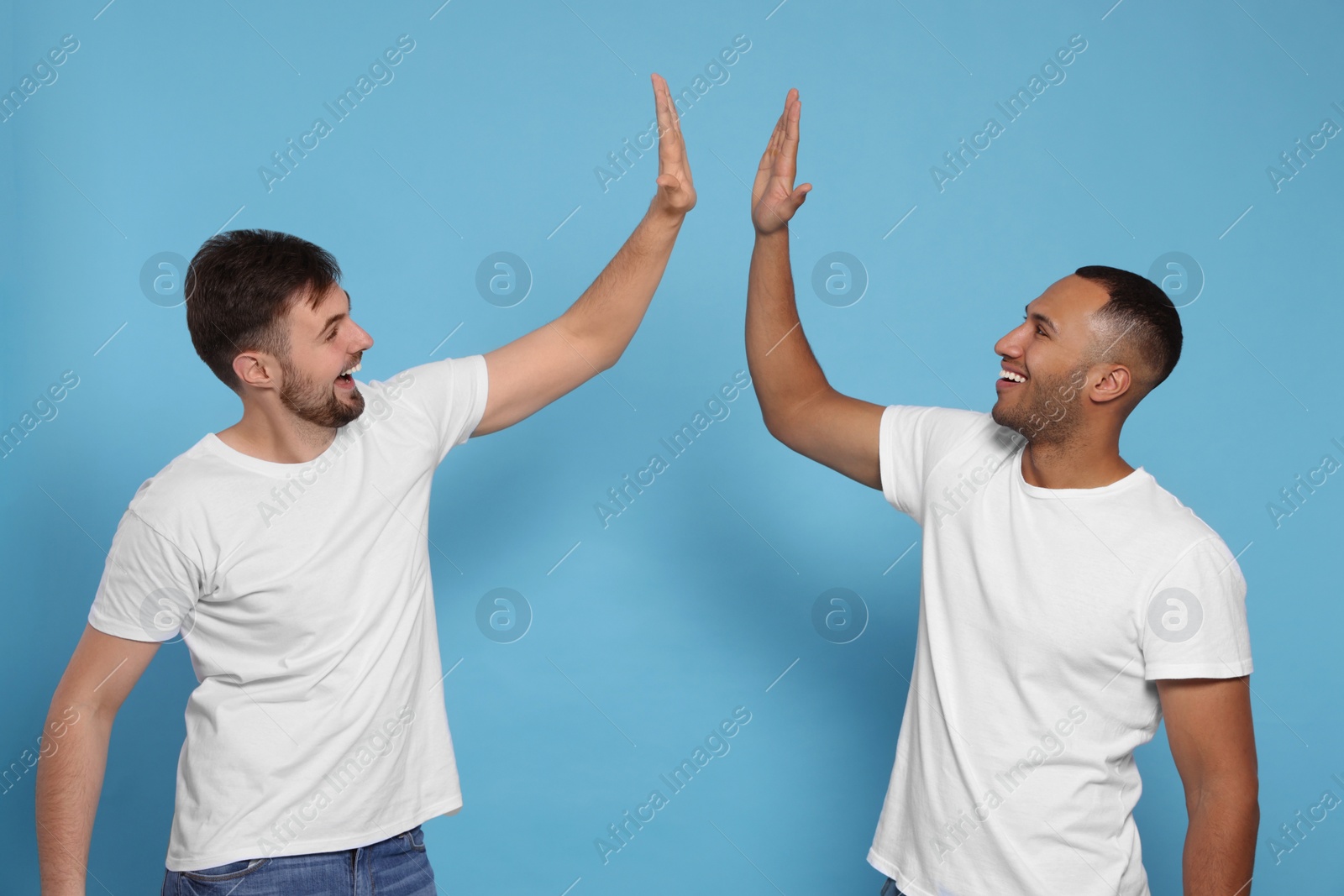 Photo of Men giving high five on light blue background