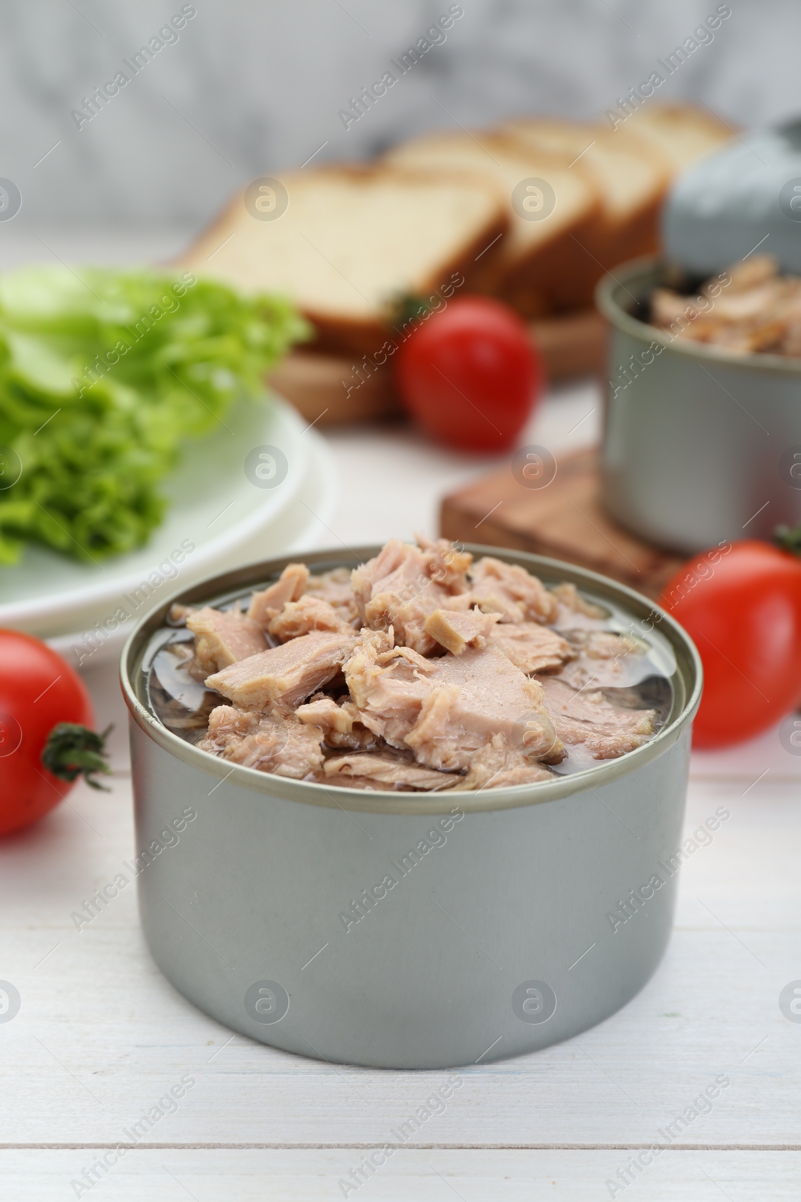 Photo of Tin can with canned tuna on white wooden table