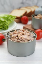 Photo of Tin can with canned tuna on white wooden table