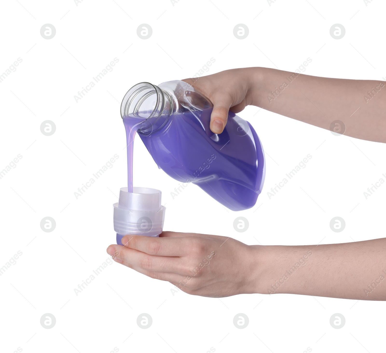 Photo of Woman pouring fabric softener from bottle into cap on white background, closeup