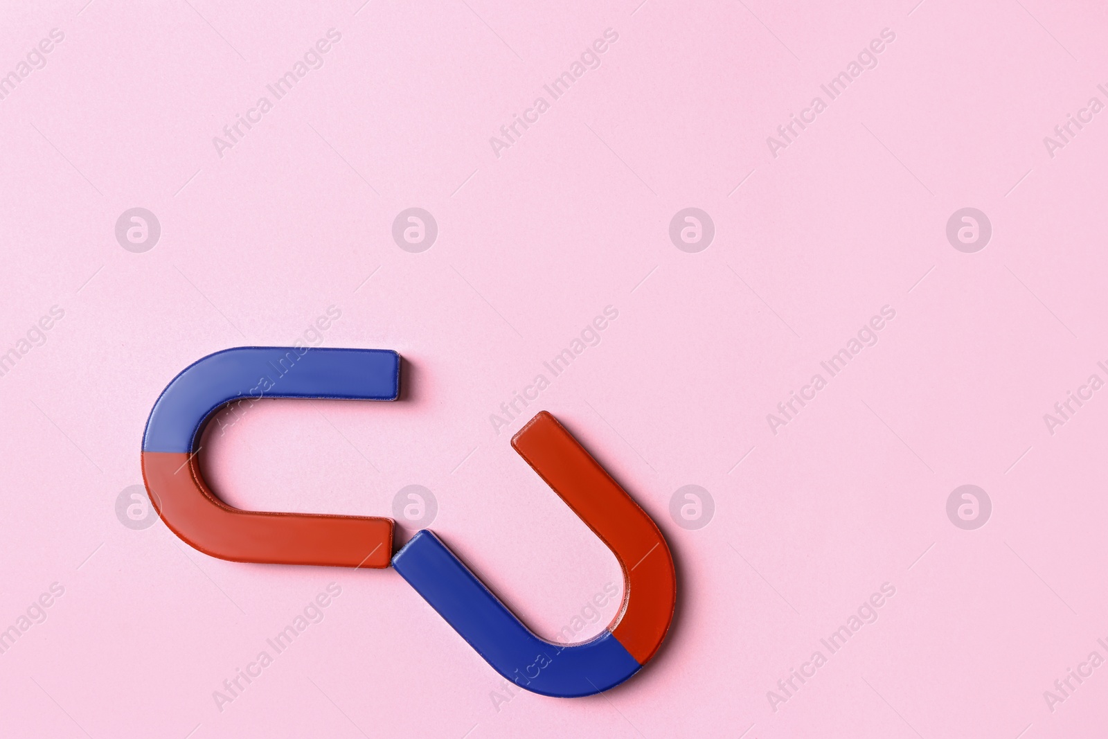 Photo of Red and blue horseshoe magnets on pink background, flat lay. Space for text