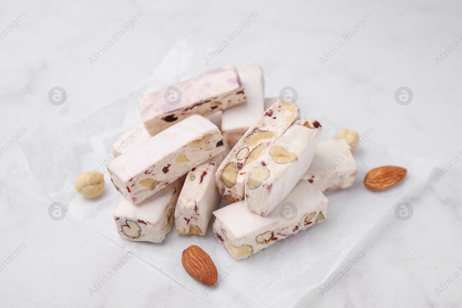 Photo of Pieces of delicious nutty nougat on white table
