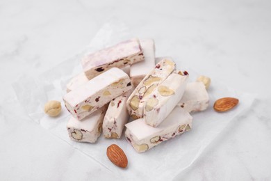 Photo of Pieces of delicious nutty nougat on white table