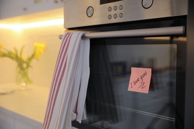 Sticky note with handwritten text I Love You attached to oven door in kitchen. Romantic message