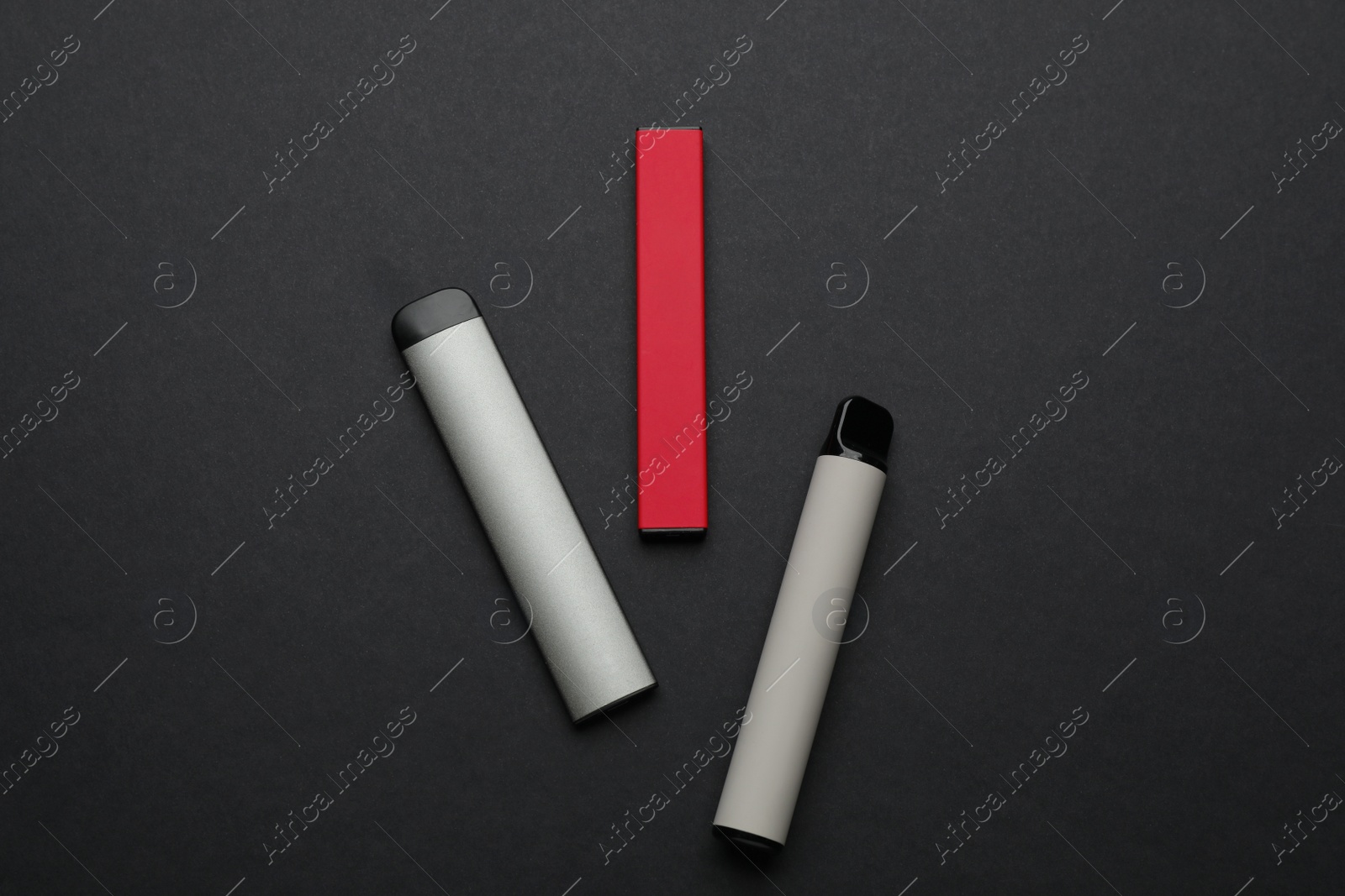 Photo of Disposable electronic smoking devices on black background, flat lay
