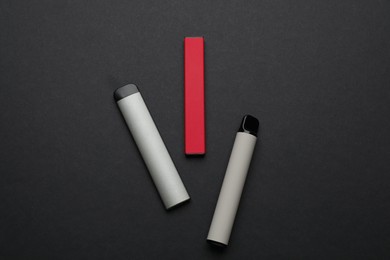 Photo of Disposable electronic smoking devices on black background, flat lay