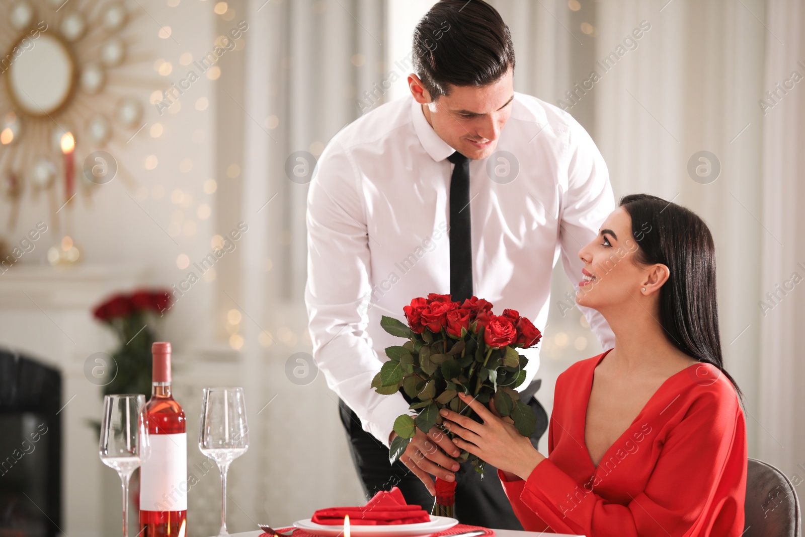 Photo of Man presenting roses to his beloved woman in restaurant. Romantic Valentine's day dinner