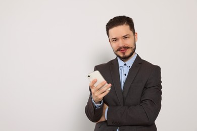 Photo of Smiling man in suit with smartphone against light grey background. Space for text