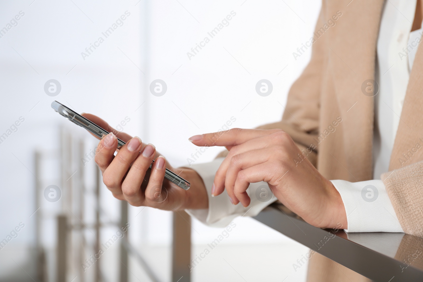 Photo of Young woman using modern smartphone indoors, closeup